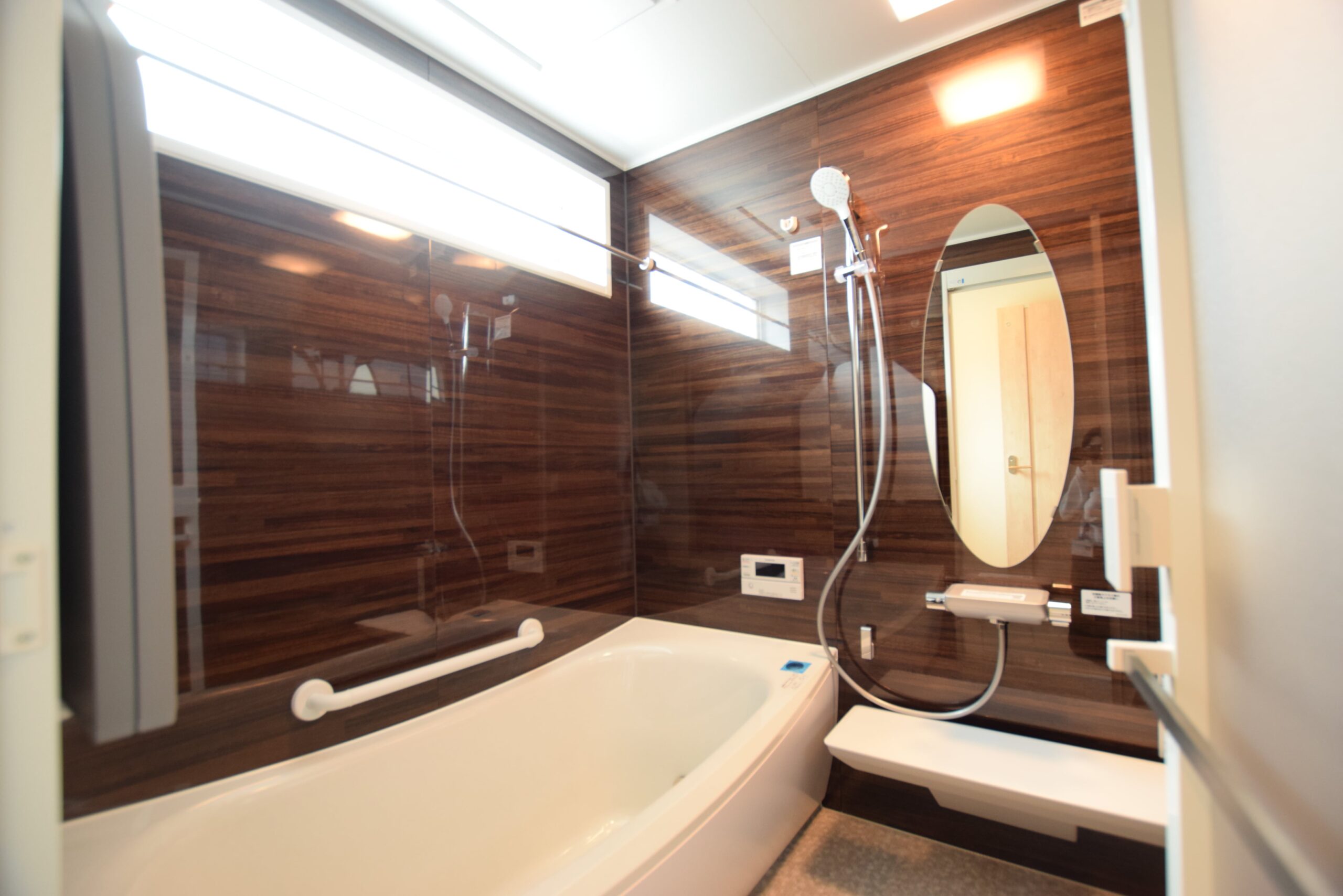 木目調パネルと楕円形の鏡で高級感溢れる浴室に<br/>
TOTOサザナ　ファルティウッド